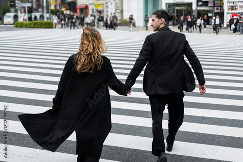 Couple holding hands crossing urban zebra stripes photo