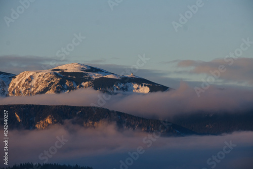 Big mountains in sunset lights with line of fog below the peak. photo