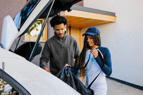 Family loading sports bag into car trunk for weekend activities