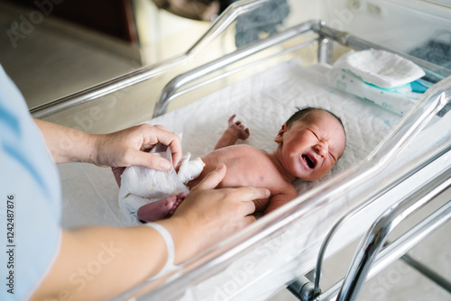 Nurse cleaning newborn baby after cesarean section in hospital crib