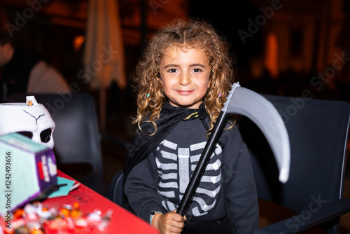 Smiling girl wearing halloween grim reaper costume holding