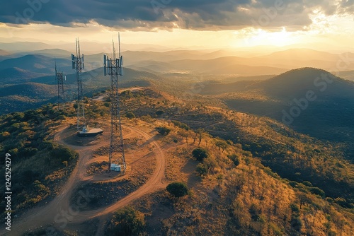 Three cell towers stand atop a hill, sunset casting long shadows. Ideal for themes of communication, technology, and remote locations.