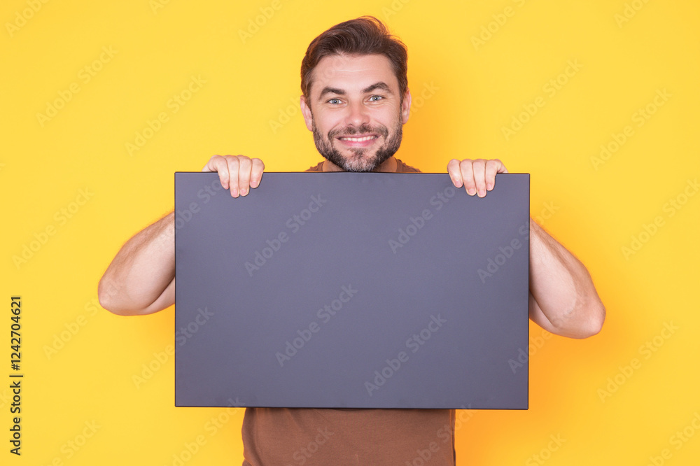 Happy guy with blank banner ad isolated on studio background. Portrait of smiling man holding empty blank poster. Man showing blank poster. Male presenting signboard, billboard or banner. Happy guy with blank banner ad isolated on studio background. Portrait of smiling man holding empty blank poster. Man showing blank poster. Male presenting signboard, billboard or banner.