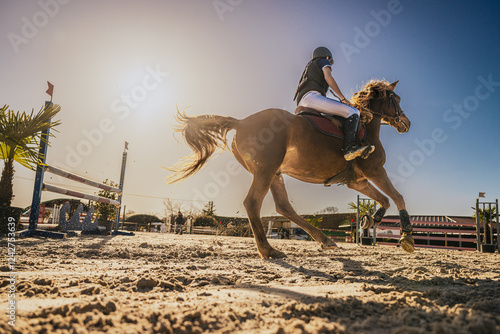 Spectaculaire contre-plongée d'un cavalier et de son cheval en plein mouvement sur un terrain de compétition équestre.