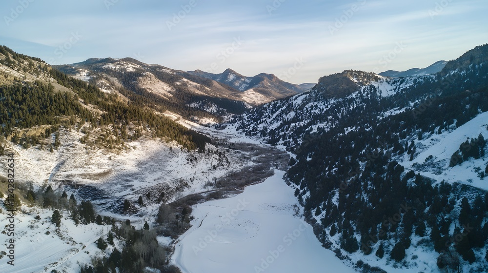 Obraz premium Snow-covered mountains under a clear sky, serene winter landscape with a river flowing through valleys, perfect for nature enthusiasts.