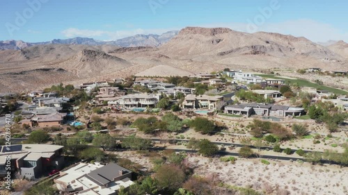 Establishing pan of car passing house community on the edge of desert mountain in southwest photo