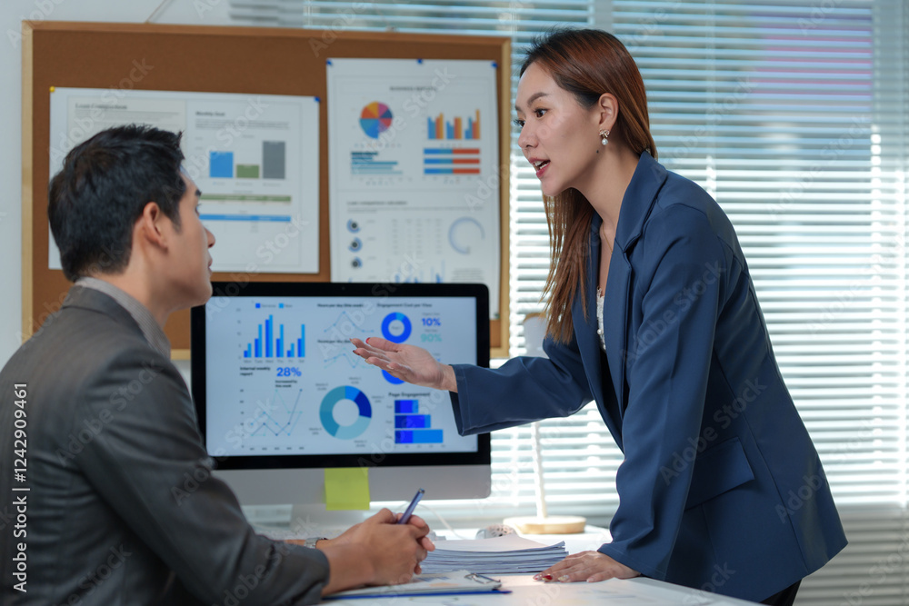 Businesswoman explaining financial charts on a computer to a male colleague in a modern office, engaging in a discussion about data analysis and corporate strategy Businesswoman explaining financial charts on a computer to a male colleague in a modern office, engaging in a discussion about data analysis and corporate strategy
