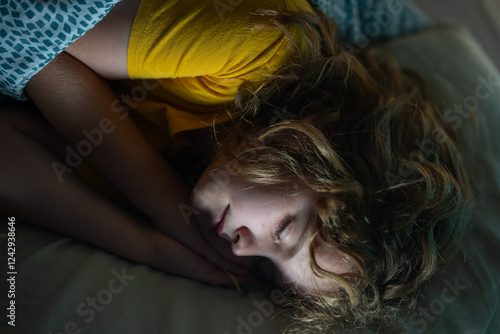 Child sleeping in a bed. Cute kid sleep. Kids pillow and blanket for sleeping. Little boy sleeps. Adorable kid sleeps in bed. Kid sleeping in dark bedroom. Child sleeping on a bed at home. photo