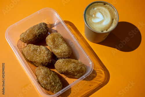 Gemblong, Indonesian sweet snack, in a clear plastic container on an orange surface. photo