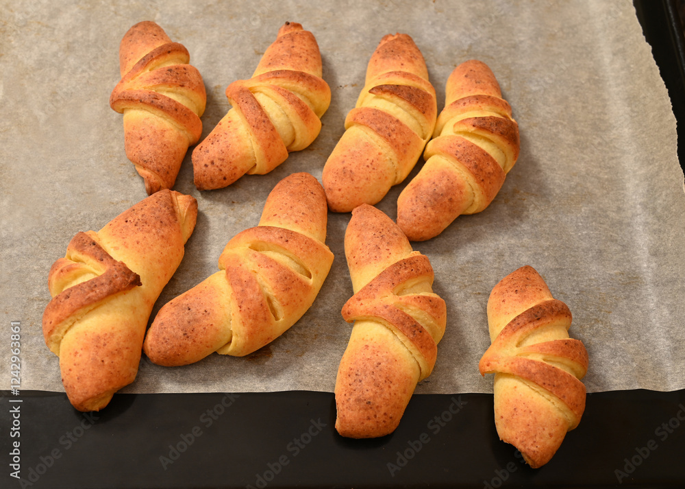 Freshly baked croissants cooling on a baking tray in a kitchen setting during the afternoon