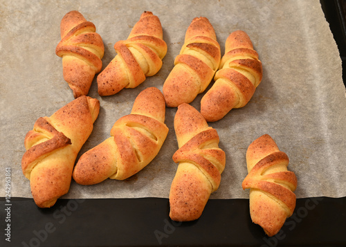 Obraz na płótnie Freshly baked croissants cooling on a baking tray in a kitchen setting during the afternoon w salonie