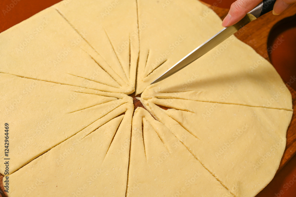 Dough preparation for a delicious baked treat with careful slicing technique in a cozy kitchen setting