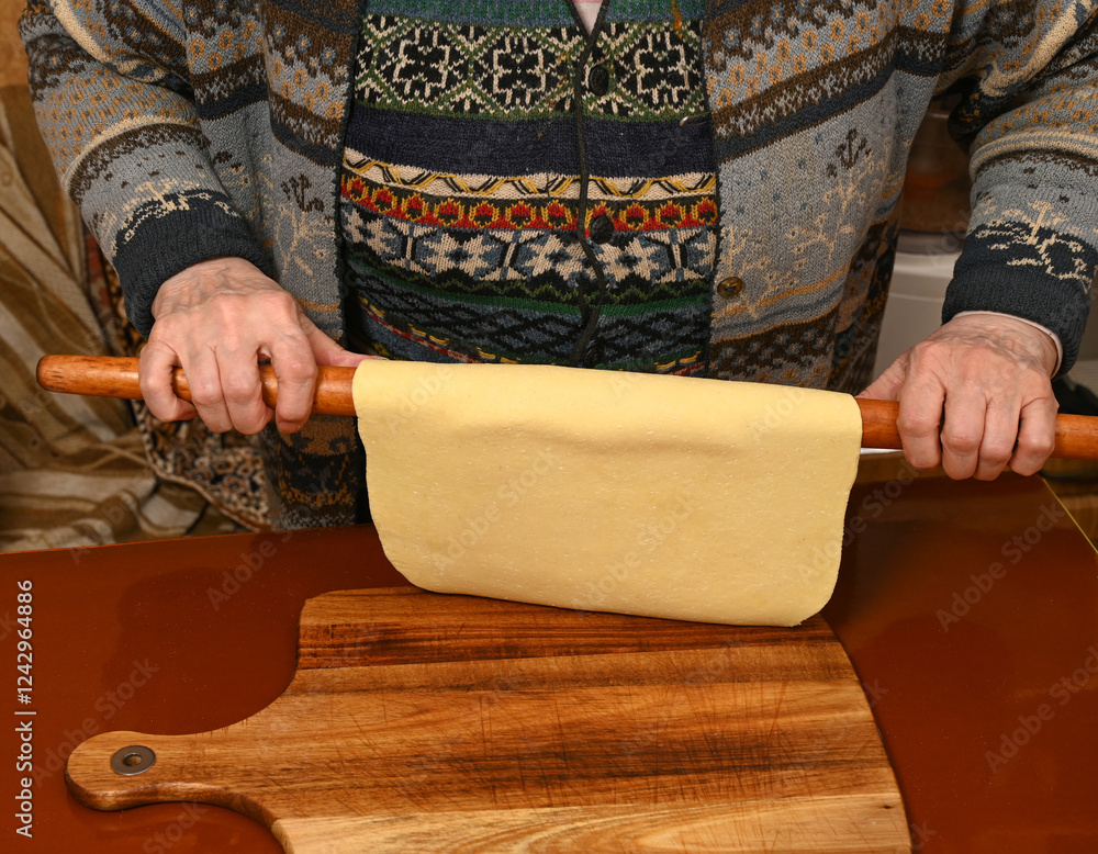 Homemade pasta preparation with a wooden rolling pin by a skilled cook in a cozy kitchen at midnight