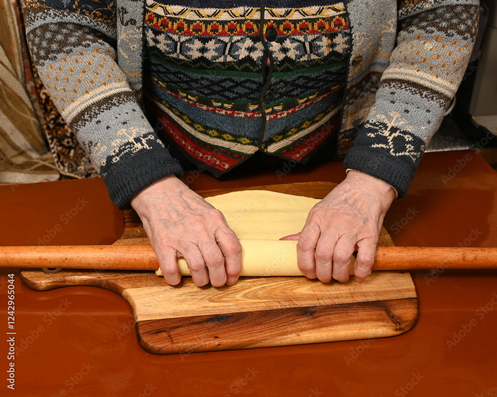 Cooking preparation with hands rolling dough on wooden surface in cozy kitchen setting