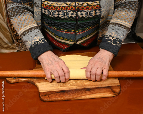 Obraz na płótnie Cooking preparation with hands rolling dough on wooden surface in cozy kitchen setting w salonie