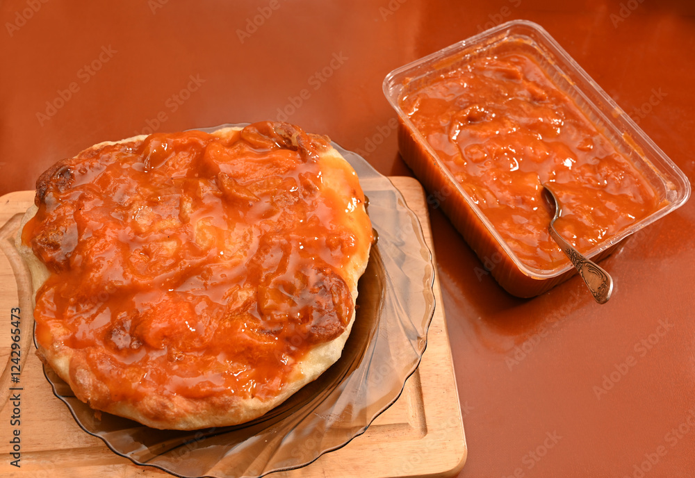 A delicious baked bread is presented on a glass plate, generously topped with jam