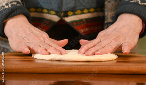 Obraz na płótnie Woman preparing dough on a wooden surface in a cozy kitchen environment while wearing a warm sweater w salonie