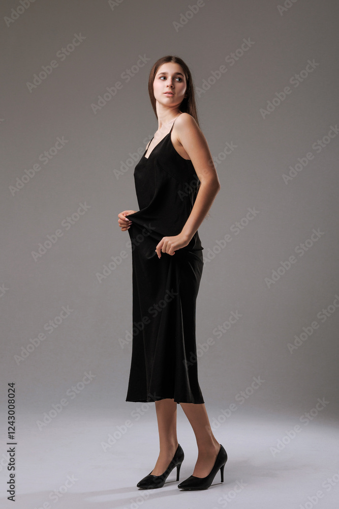 Elegant woman poses in black dress with a confident stance in a minimalist studio setting Elegant woman poses in black dress with a confident stance in a minimalist studio setting