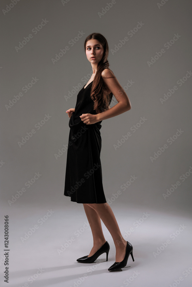 Model showcasing elegant black dress and heels in studio setting during fashion presentation Model showcasing elegant black dress and heels in studio setting during fashion presentation