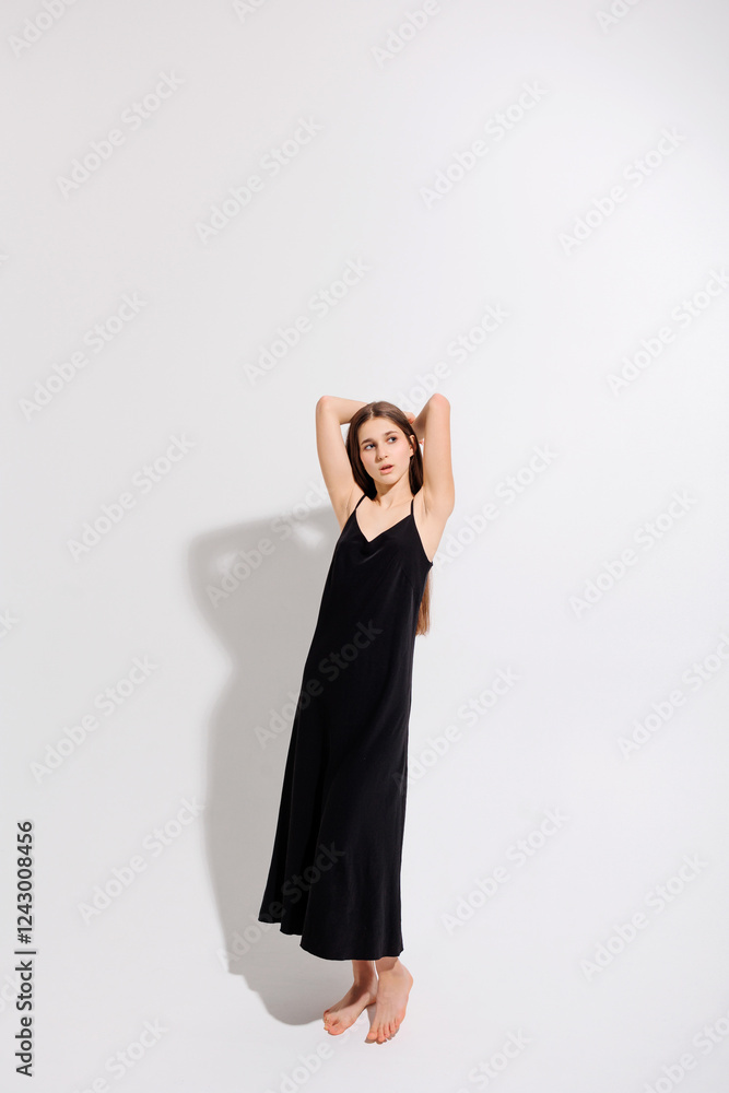 Elegant woman in black dress poses gracefully against a neutral backdrop Elegant woman in black dress poses gracefully against a neutral backdrop
