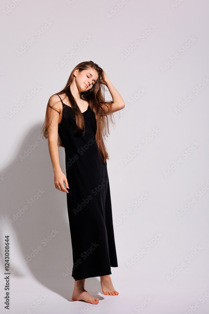 Young woman poses elegantly in a black dress against a minimalist backdrop in a studio setting Young woman poses elegantly in a black dress against a minimalist backdrop in a studio setting