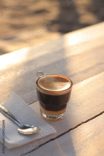 Coffee Cup Sits on a Wooden Table with a Spoon Nearby, Perfectly Capturing the Essence of a Relaxing Morning