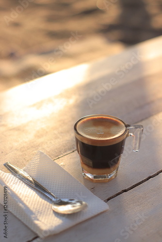 Coffee Cup Sits on Table with Spoon and Napkin in Morning Sunlight
