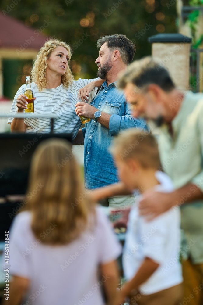 Obraz premium Family having a barbecue party and talking in the backyard
