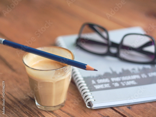 Coffee, Pencil, Notebook, and Glasses Create a Cozy Workspace on a Wooden Table for Creative Inspiration.