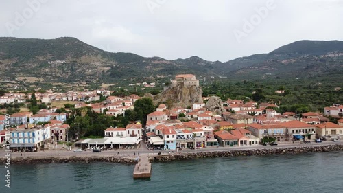 Petra village street with local tavernas, shops, Virgin Mary Greek Orthodox church atop rock surrounding mountains, Olive groves garden, Lesbos Island, Aegean sea, Aerial, Establishing, Panoramic view photo