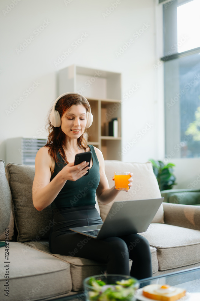 Happy woman with headphones using a laptop in a cozy living room with food and drink. Perfect for themes Happy woman with headphones using a laptop in a cozy living room with food and drink. Perfect for themes