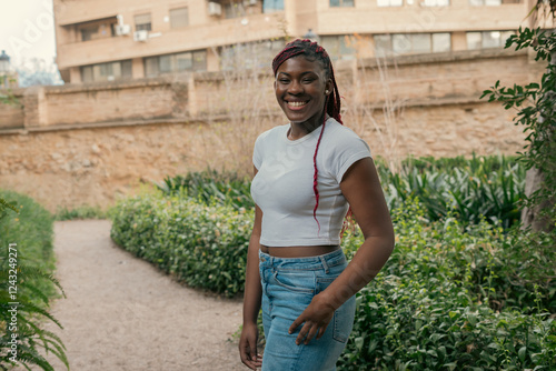 Young black woman smiling in a park near a stone wall photo