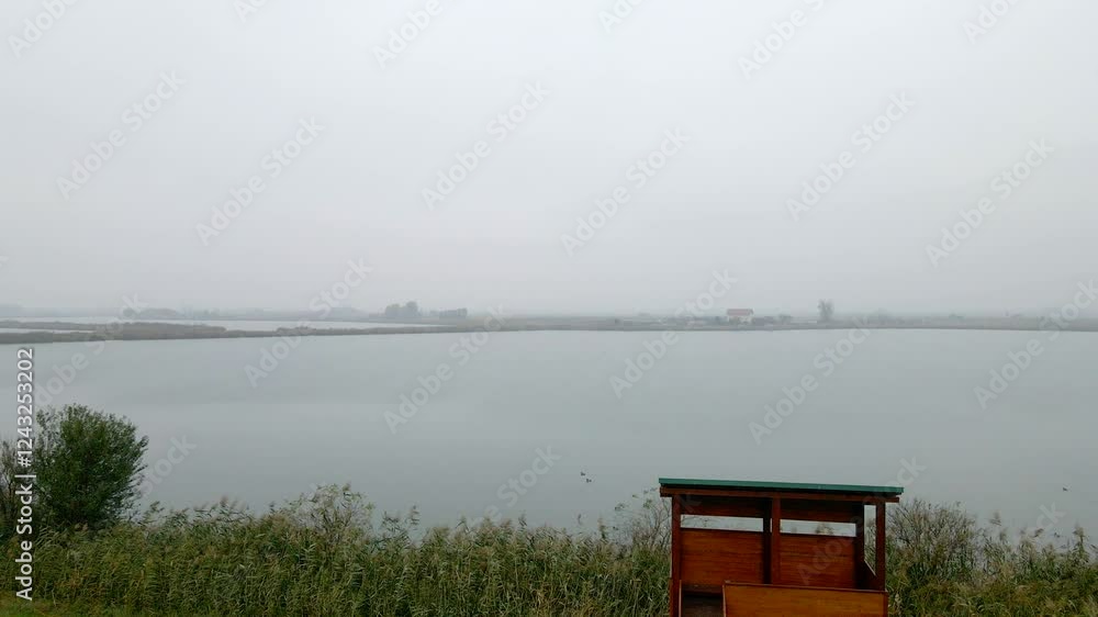 Misty morning over calm water with small islands in the distance near a coastal area