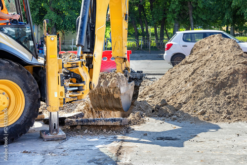 Obraz na płótnie Excavator digging up asphalt on a sunny day in a busy urban street w salonie
