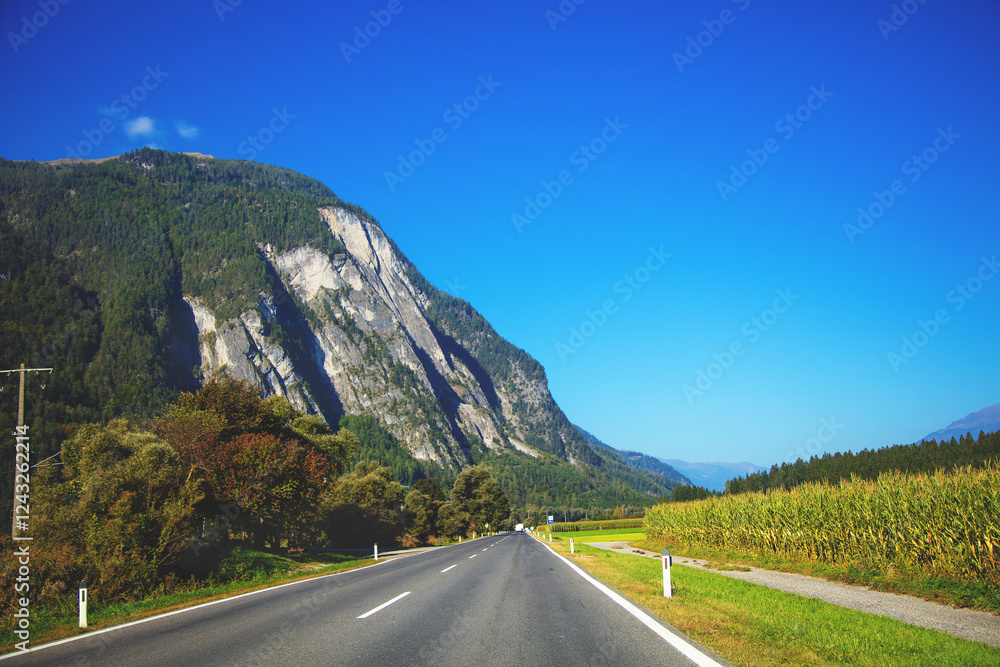 View of a beautiful mountain landscape through a windscreen on a sunny day. Driving a car on a mountain road