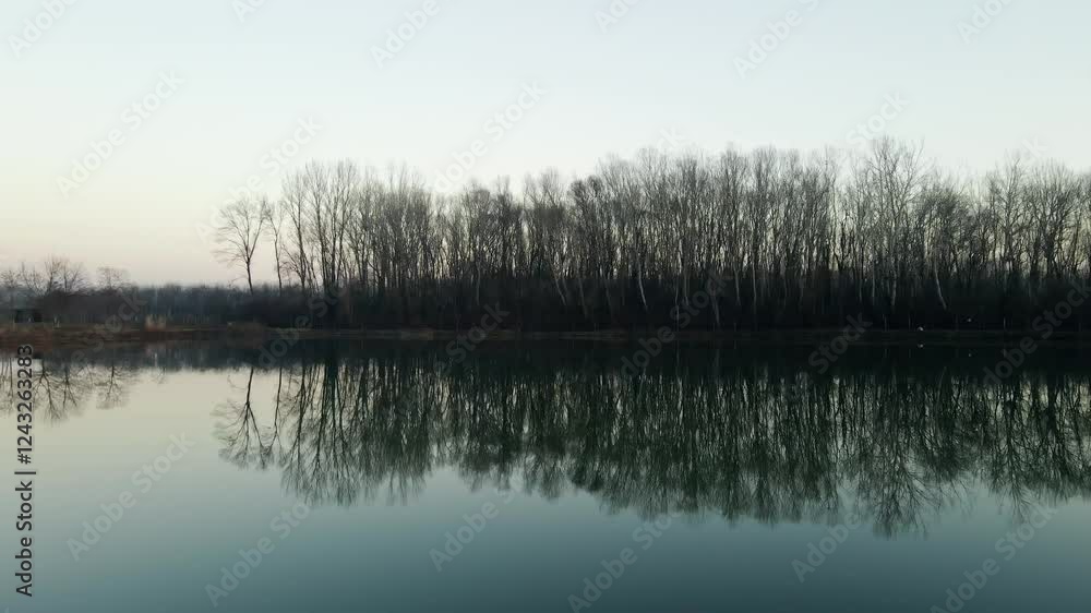 Serene lake landscape with reflection of trees on calm water during early morning light in nature setting Serene lake landscape with reflection of trees on calm water during early morning light in nature setting