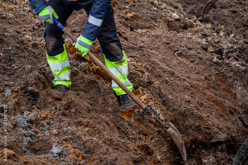 Naklejka premium Man professional construction road digger worker to digging a trench of earth ground. Road construction digging works in professional construction worker clothes