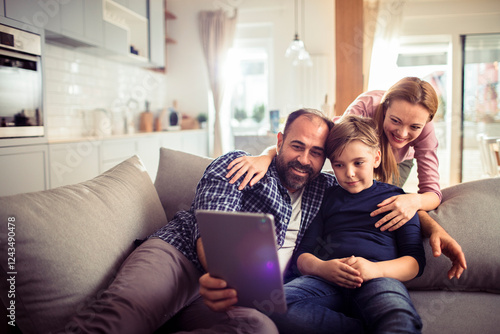 Young family using a digital tablet while sitting on the couch in the living room