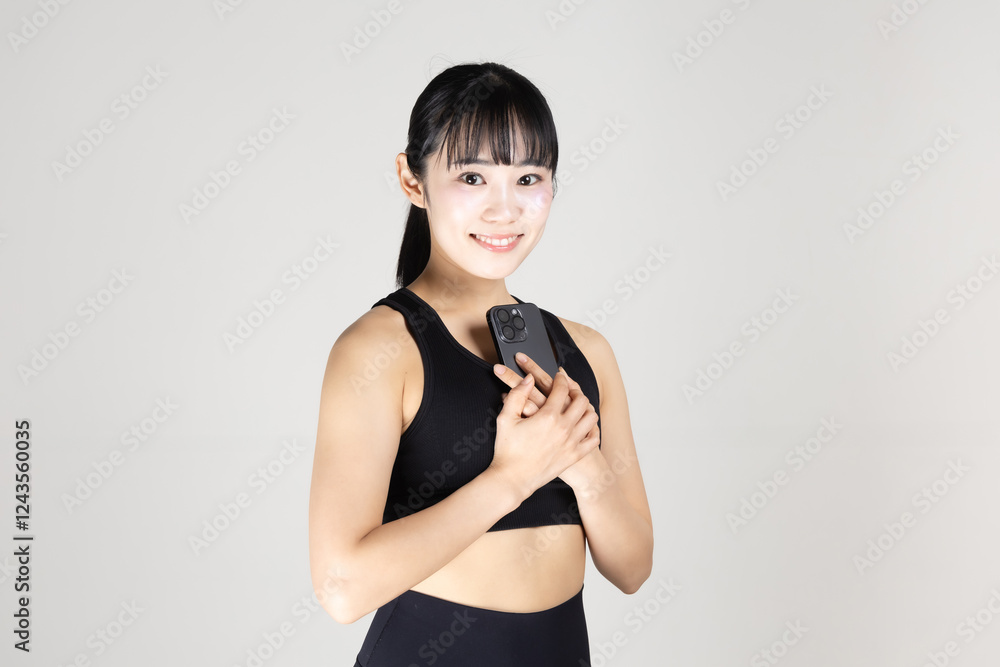 Naklejka premium スマートフォンを手に持っているスポーツウェアの女性