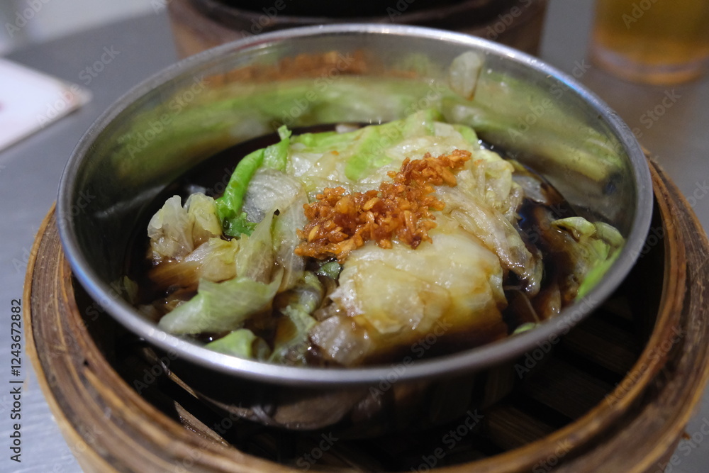 Steamed lettuce with soy sauce and crispy garlic, served in a metal bowl on a bamboo steamer, showcasing a delicious Asian dish. Steamed lettuce with soy sauce and crispy garlic, served in a metal bowl on a bamboo steamer, showcasing a delicious Asian dish.