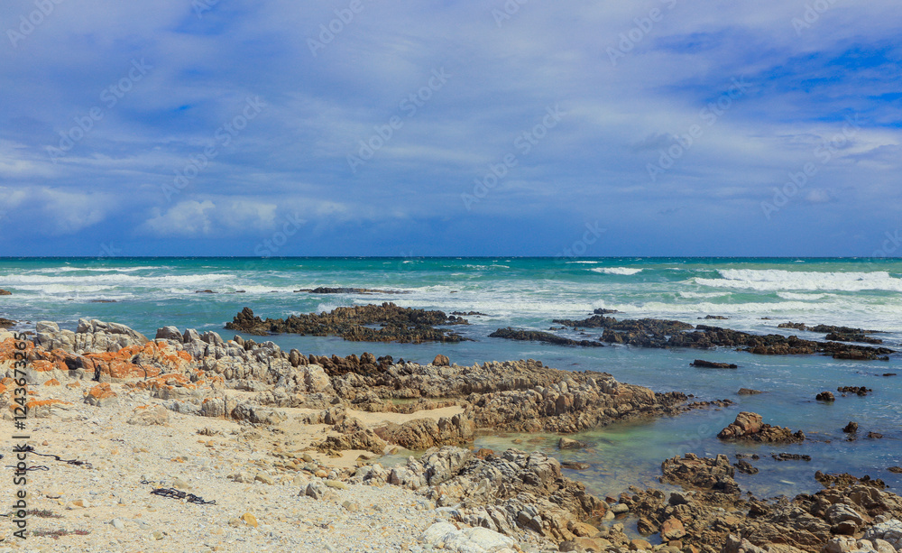 Coastal view of South African rocky shoreline with azure waves and cloudy sky at midday Coastal view of South African rocky shoreline with azure waves and cloudy sky at midday