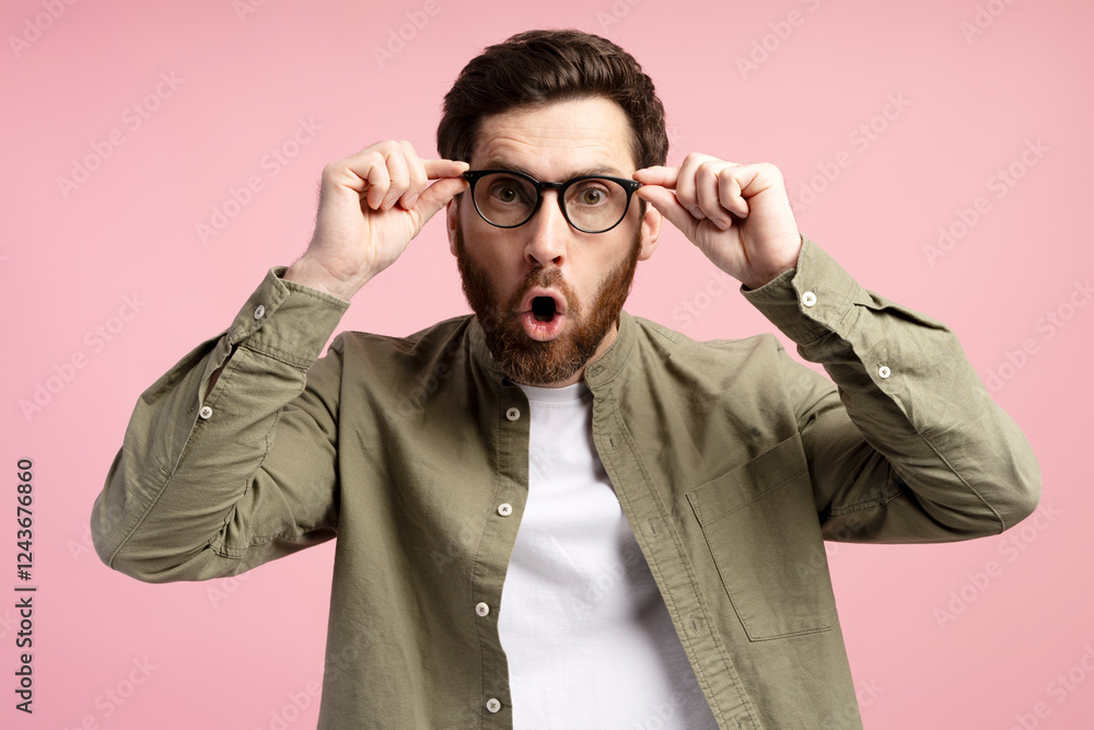 Surprised young man receiving good news, taking off his glasses, looking at camera Surprised young man receiving good news, taking off his glasses, looking at camera