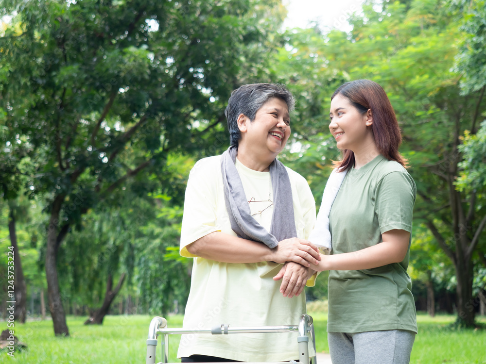 Asian senior woman holding a walker and walking with daughter in the park. healthy of elder woman. Asian senior woman holding a walker and walking with daughter in the park. healthy of elder woman.