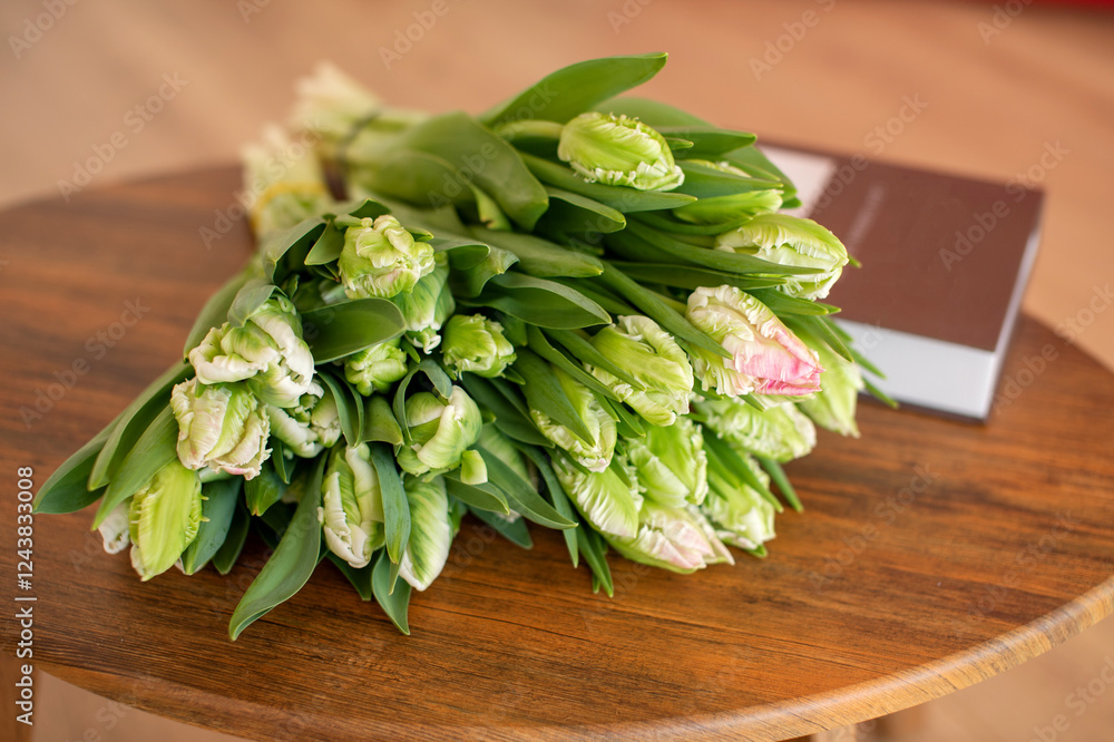 Unopened tulip bouquet on wooden table next to book. Unopened tulip bouquet on wooden table next to book.