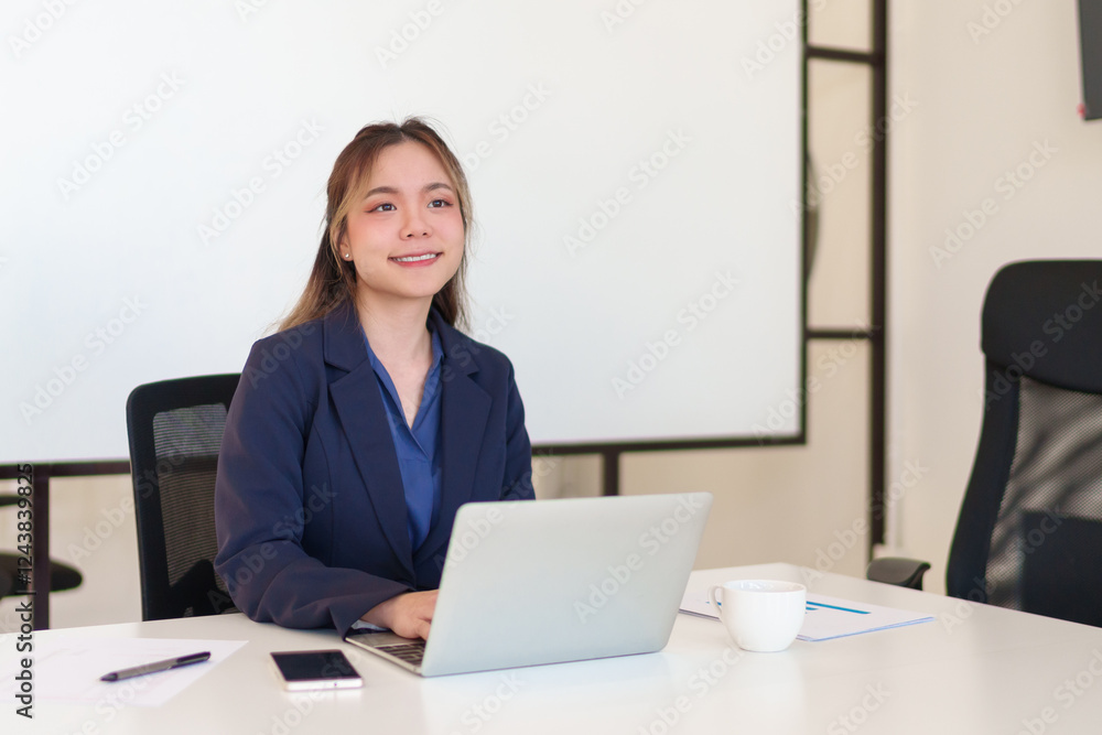 Young Asian businesswoman working on a laptop in a modern office, wearing a professional suit Young Asian businesswoman working on a laptop in a modern office, wearing a professional suit