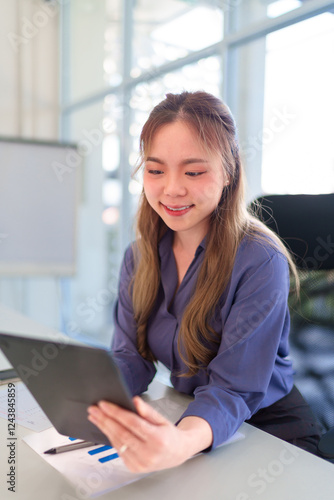 Close-up of a young Asian businesswoman holding a tablet and gesturing while discussing business data in a modern office Free Download Close-up of a young Asian businesswoman holding a tablet and gesturing while discussing business data in a modern office - GFXLoad
