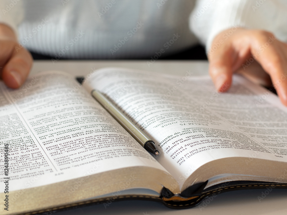 Christian woman is holding open holy bible book in her hands while studying and reading. Close-up. Selective focus. Biblical education concept. Christian woman is holding open holy bible book in her hands while studying and reading. Close-up. Selective focus. Biblical education concept.