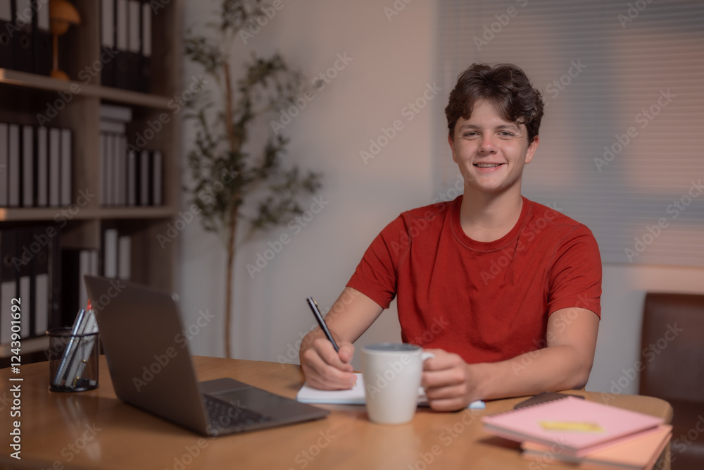 Happy teenager studying at home, using a laptop while taking notes and sipping coffee, smiling and enjoying the learning experience in a cozy, inviting room Happy teenager studying at home, using a laptop while taking notes and sipping coffee, smiling and enjoying the learning experience in a cozy, inviting room