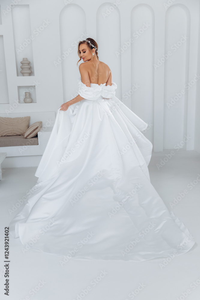 Porter from behind a young bride in a white trendy dress with a long train on a white background in the studio. Porter from behind a young bride in a white trendy dress with a long train on a white background in the studio.