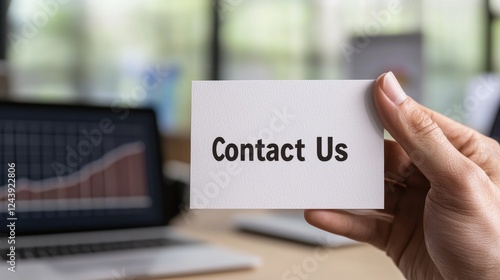 Wallpaper Mural A professional hand holds a 'Contact Us' card amidst office technology, symbolizing effective communication and customer engagement. Torontodigital.ca